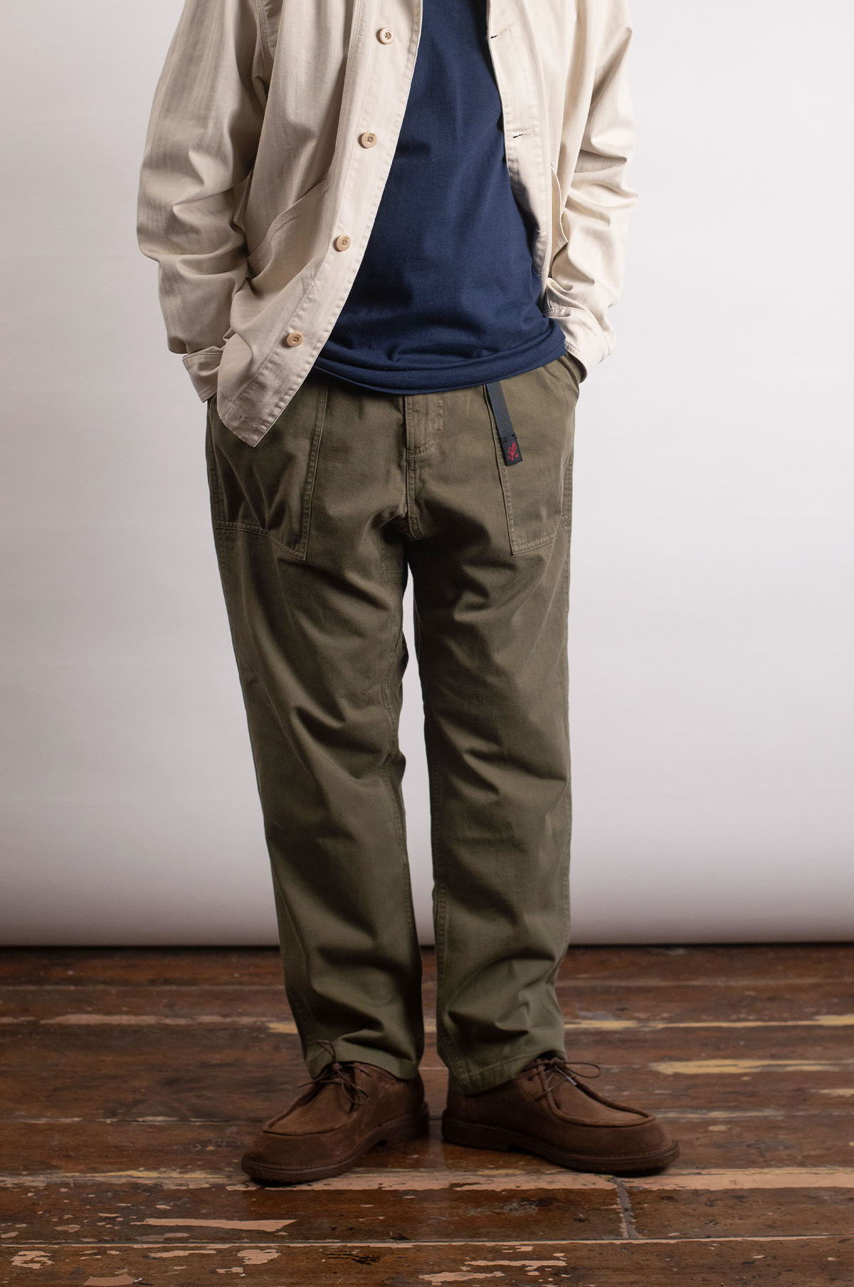 Person wearing a light jacket, blue shirt, and olive green pants.