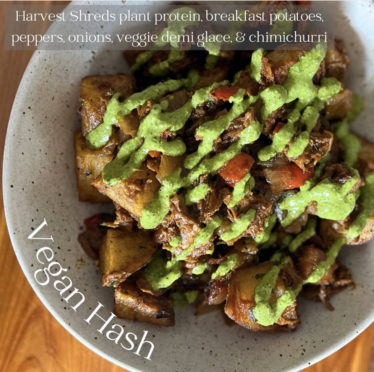 Speckled bowl filled with Harvest Shreds plant protein, breakfast potatoes, peppers, onions, veggie demi glace and a drizzle of chimichurri. Vegan Hash.