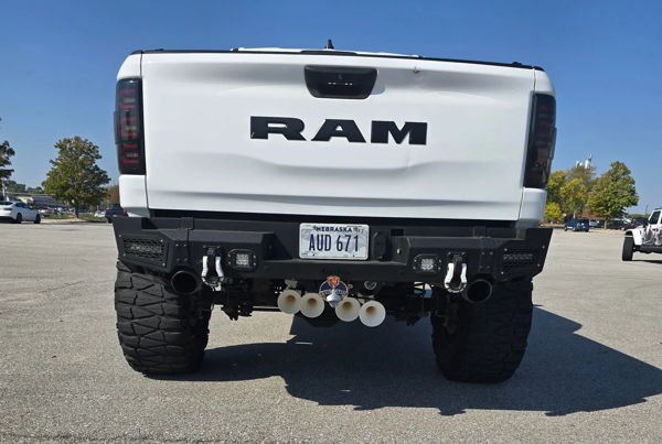 Rear view of white RAM 1500 Rebel with aftermarket bumper and four train horns mounted below