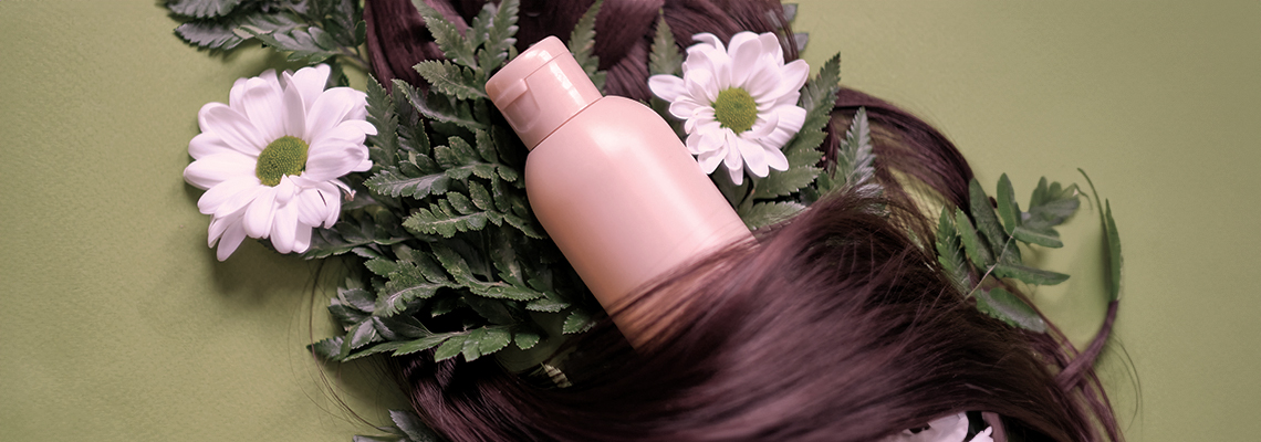 Bottle surrounded by flowers and greenery on a green background.