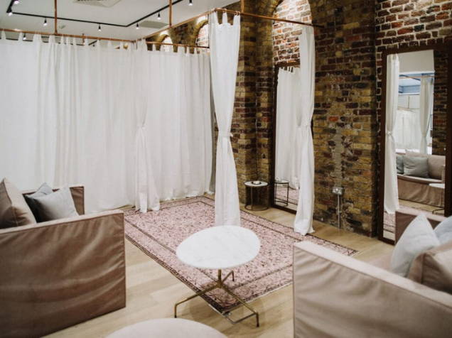 Cozy blush couches and sheer white curtains in an exposed brick room 