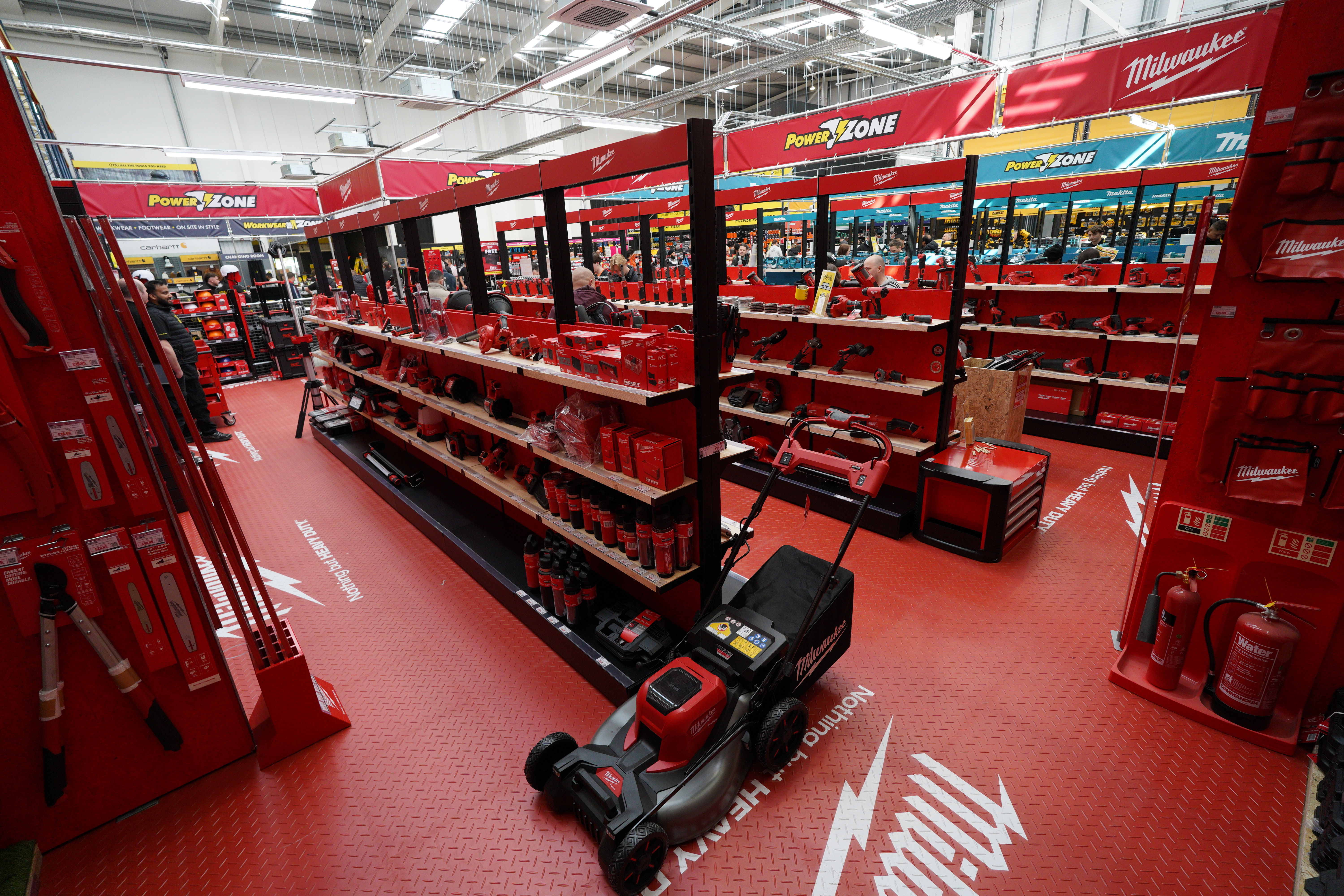 Store aisle with red shelving displaying various tools and equipment.