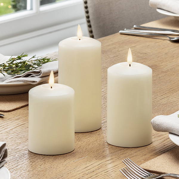 3 ivory LED pillar candles on a dining table.