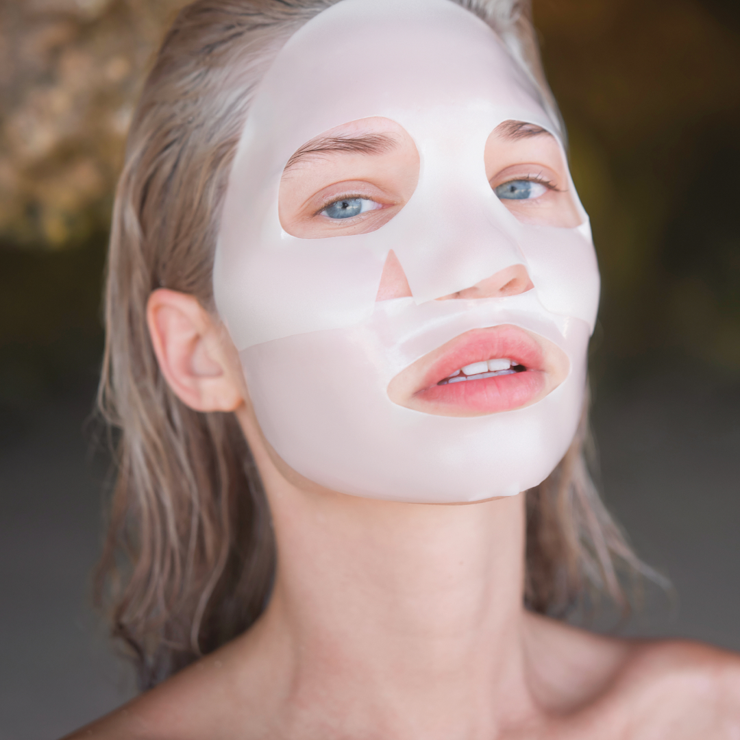 Person with a facial mask, showing clear skin and blue eyes.