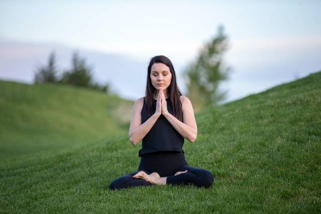 Woman Meditating On Grass