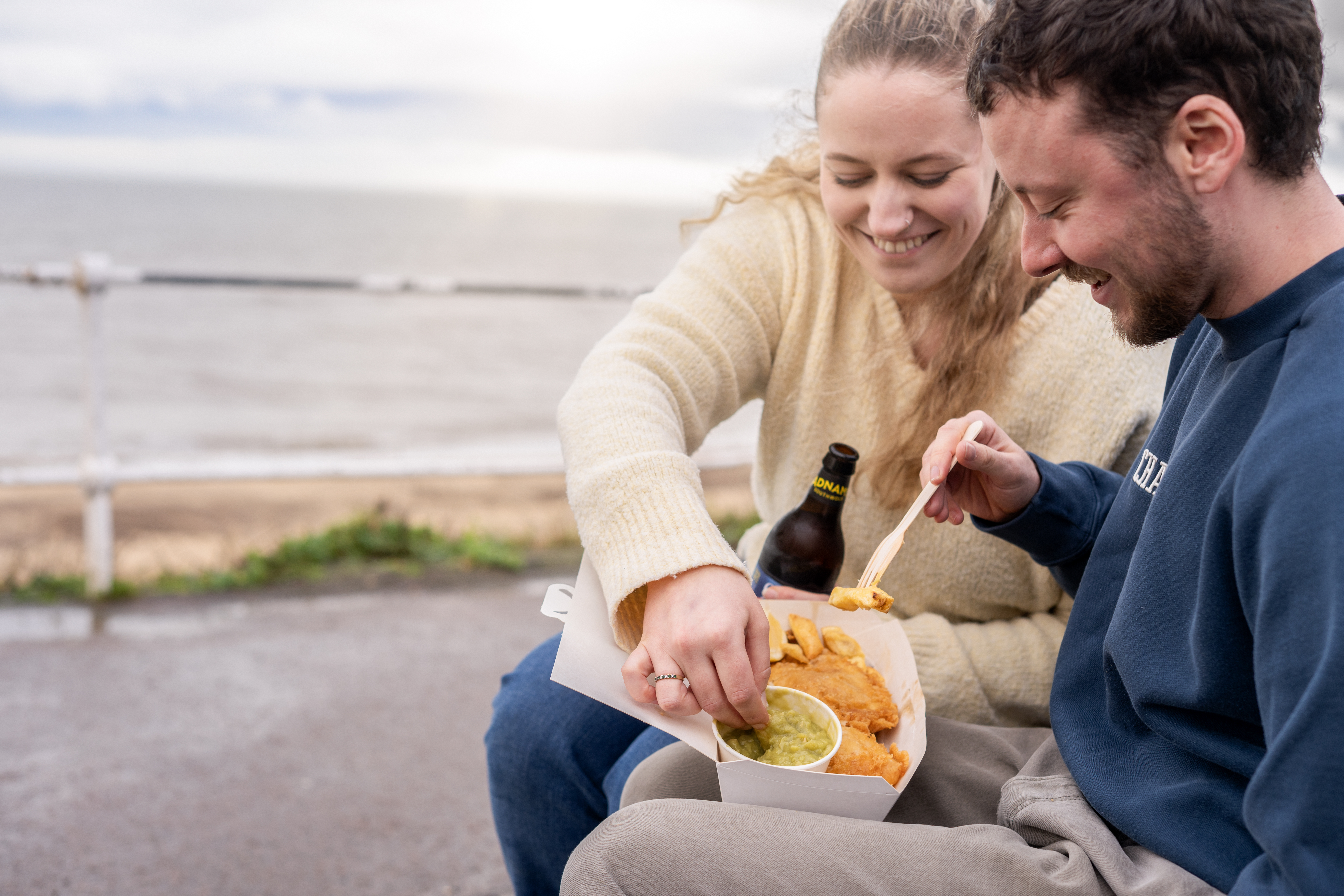 enjoying food by the seaside, sharing a fun moment together.