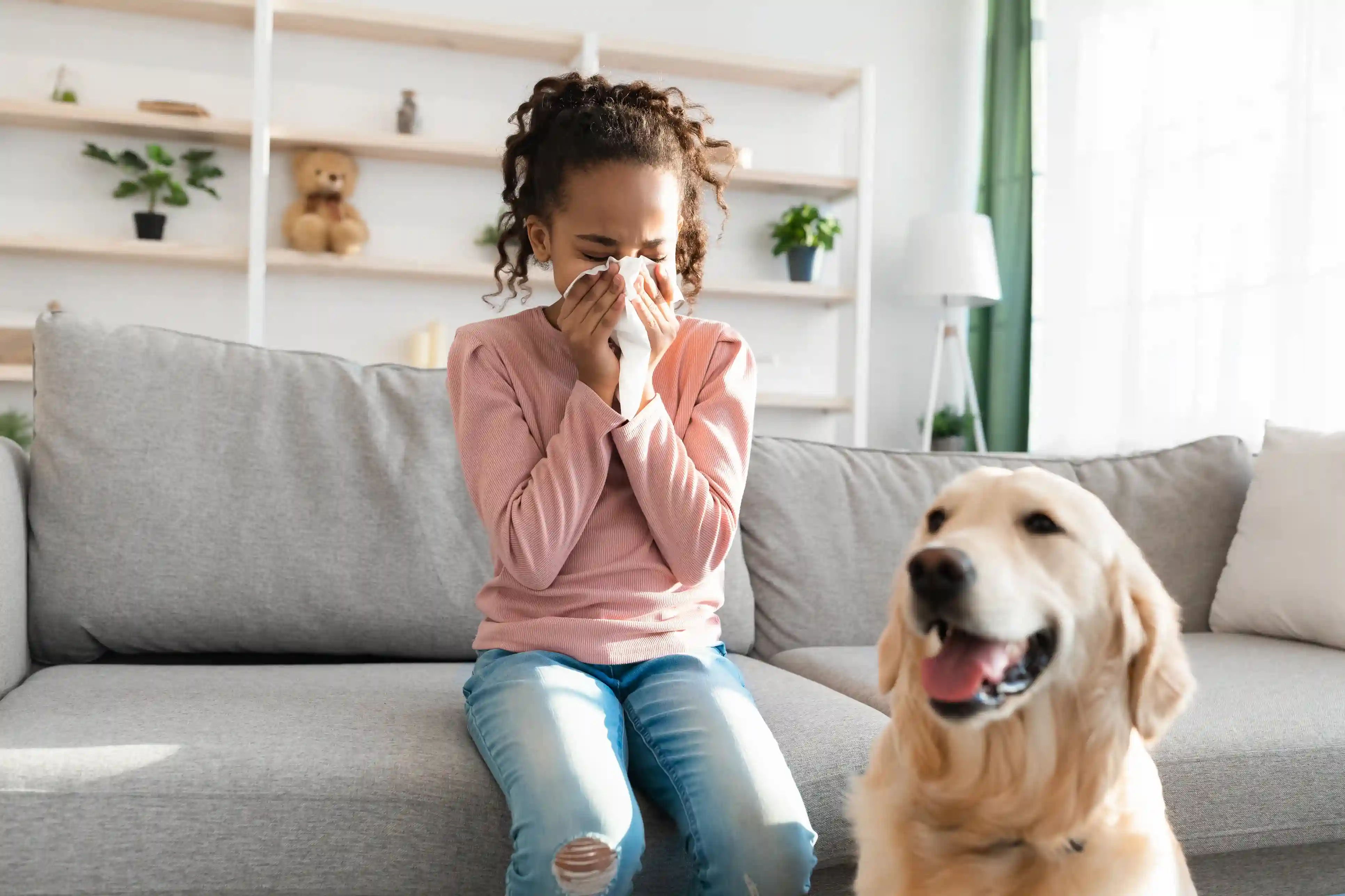 Een meisje zit naast haar hond en snuit haar neus, ze heeft last van een verstopte neus. Het kan een allergie voor huisdieren kunnen zijn.