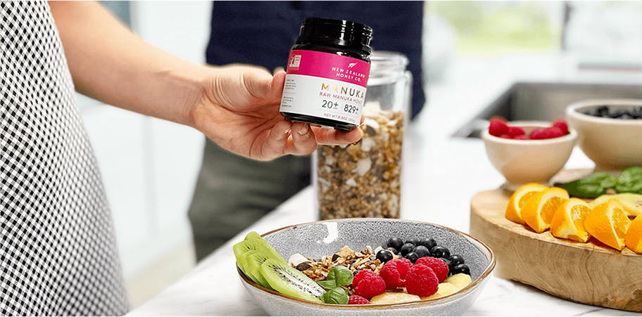 Person holding a supplement jar next to a healthy meal with fruits and granola.