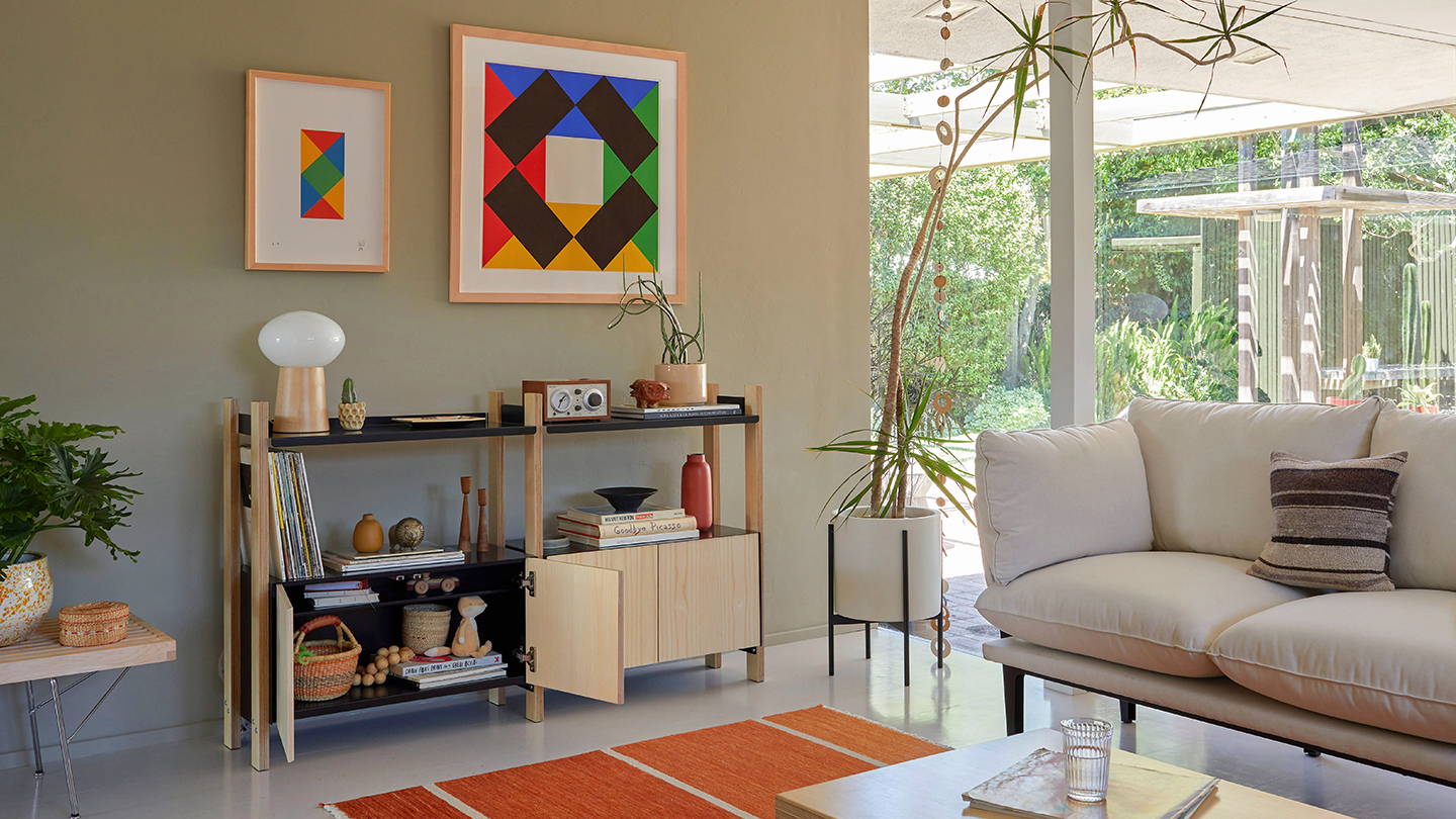 A brightly lit living room featuring The Floyd Sofa in Oat and The Floyd Shelving System
