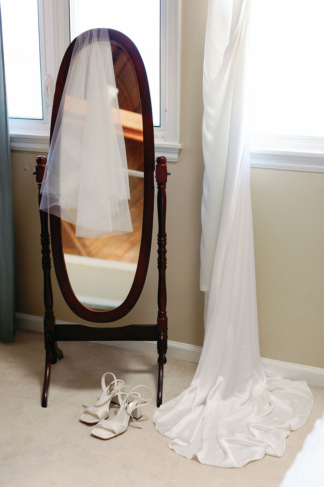 A full-length mirror with a veil and white shoes beside it.