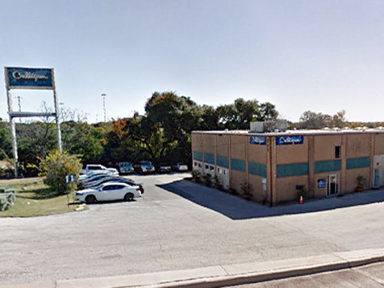 Exterior view of a lodging building with parked cars and signage.
