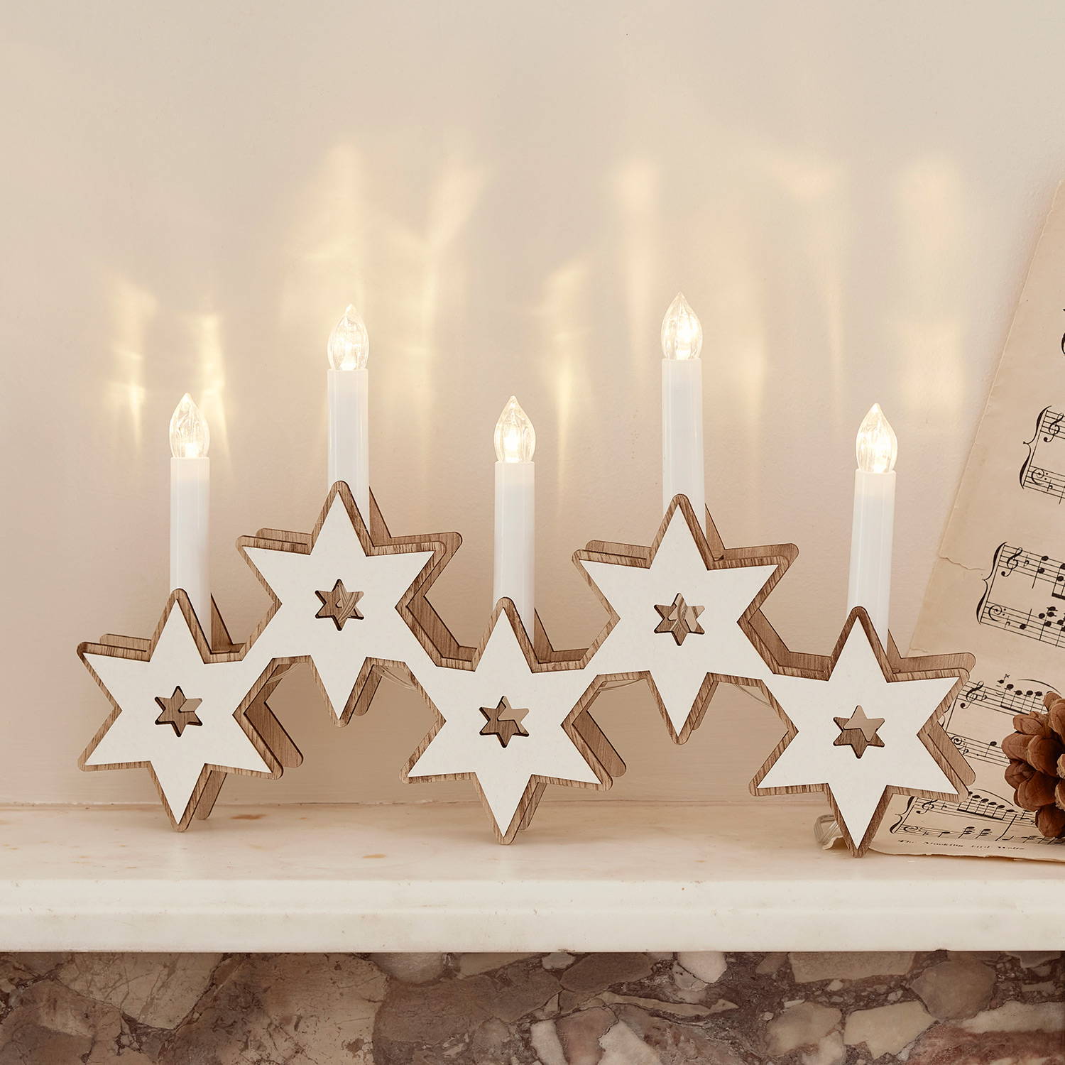 Wooden star candle bridge on a mantlepiece.
