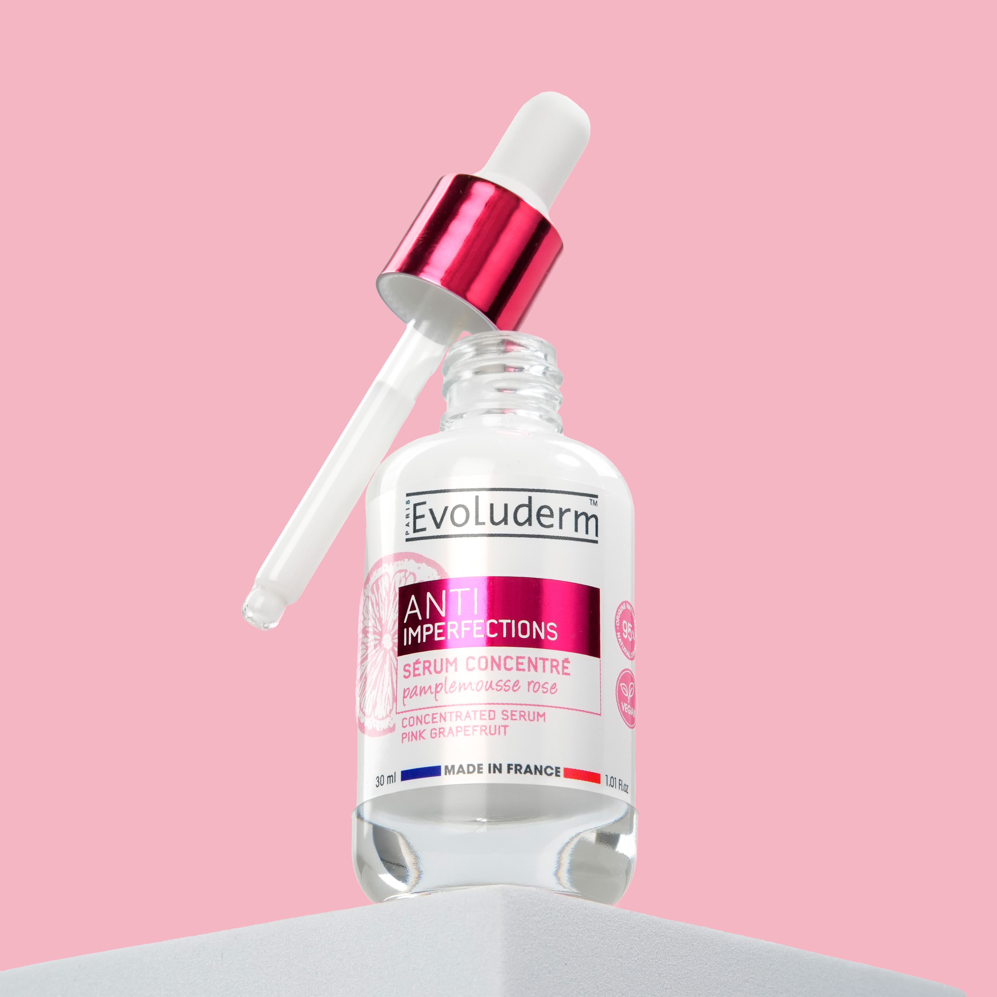 Bottle of serum with dropper on pink background.