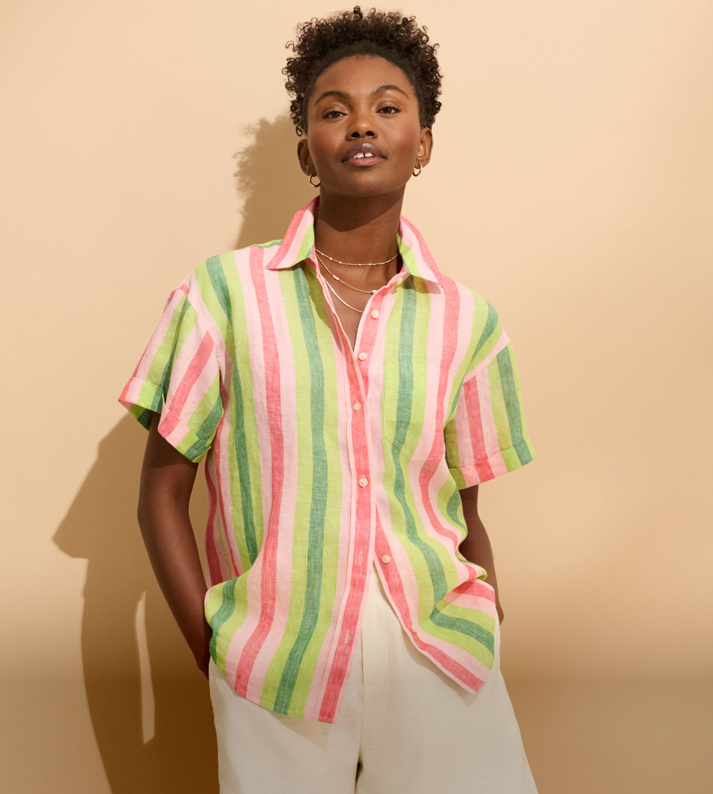 Person wearing a colorful striped shirt stands against a neutral background.