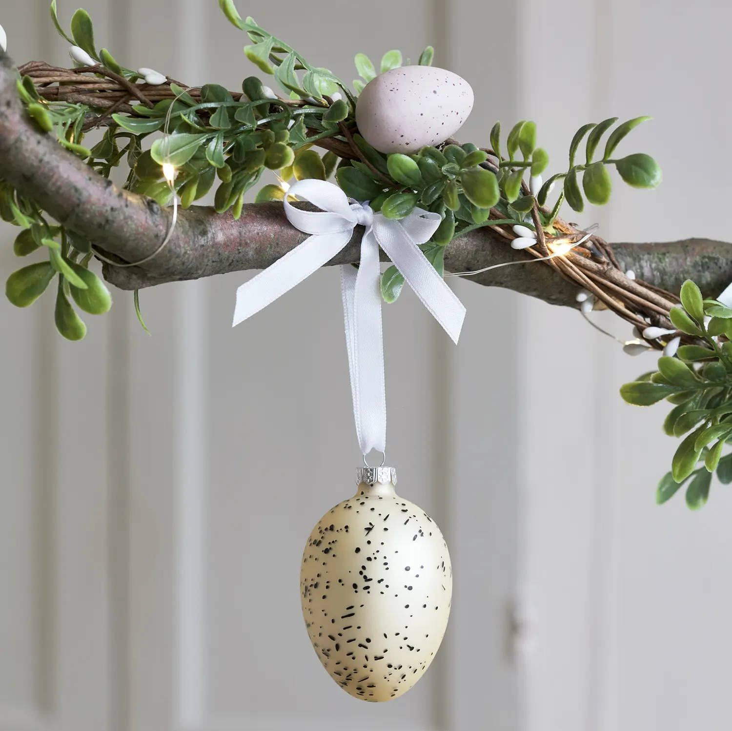 Pastel yellow Easter egg decoration hanging from Easter branch 