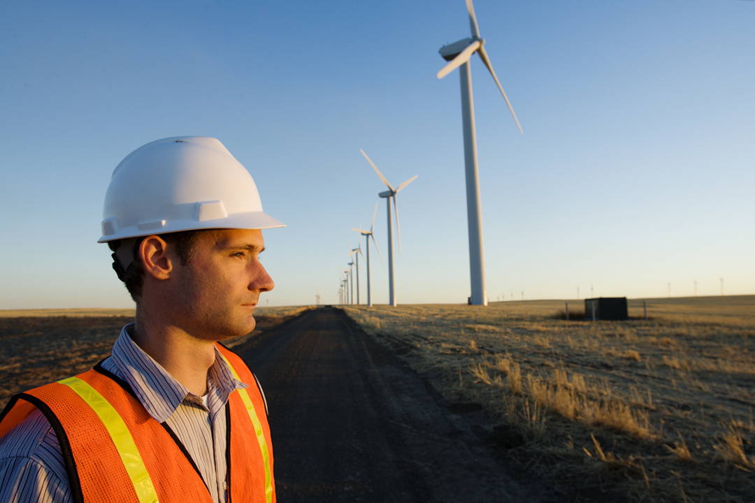 A man stands in front of a wind turbine