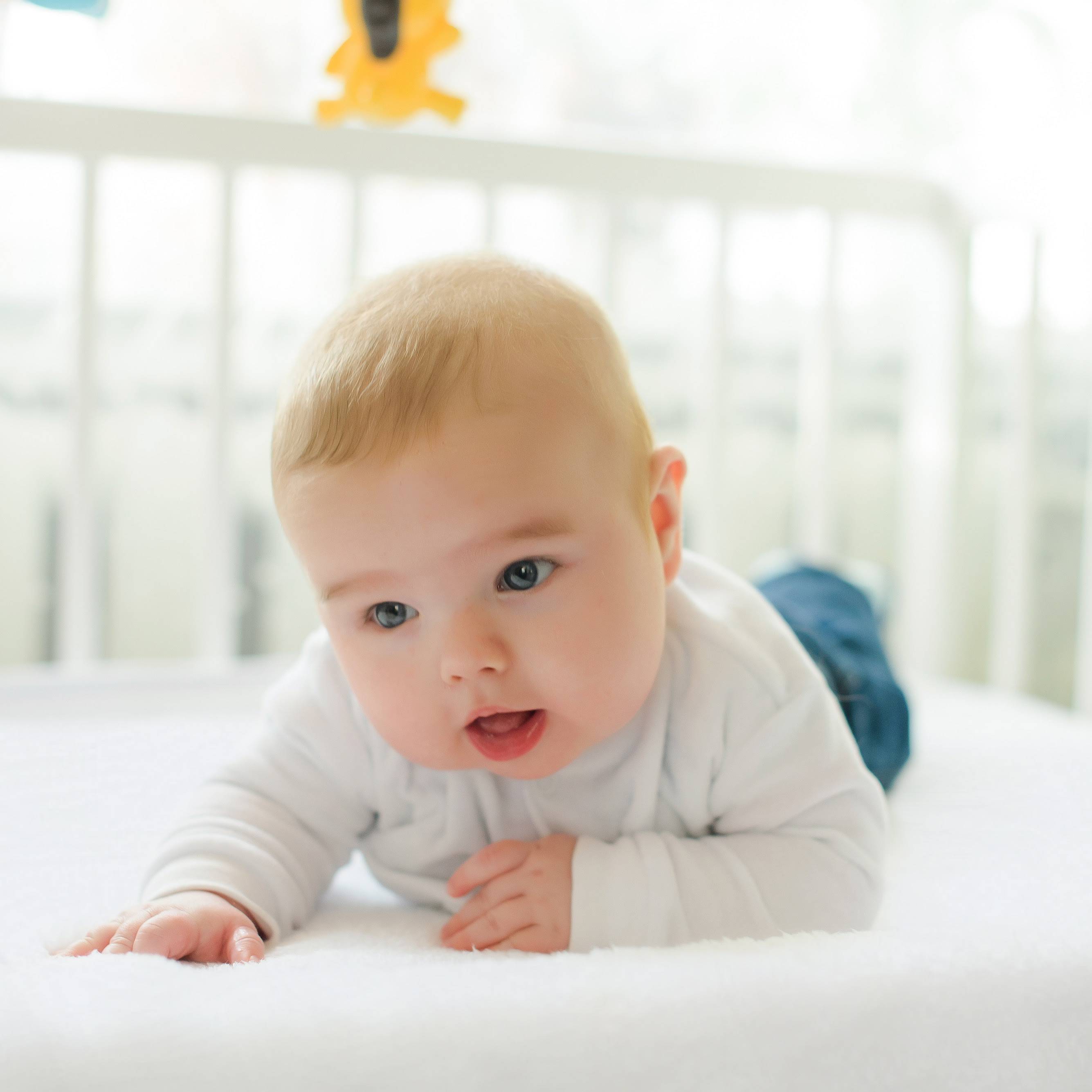 Baby boy lifting head on a comfortablly soft and breathable crib mattress.