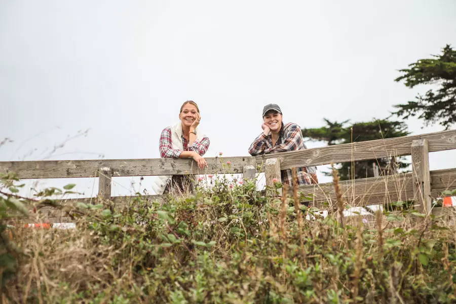 Owner Kathleen and Jr Designer Hanna lean on fence and enjoy the view of the sea.