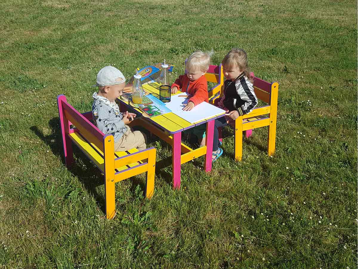 Kids playing on the kids furniture of the Wooden Playhouse Sassy Sally by WholeWoodPlayhouses