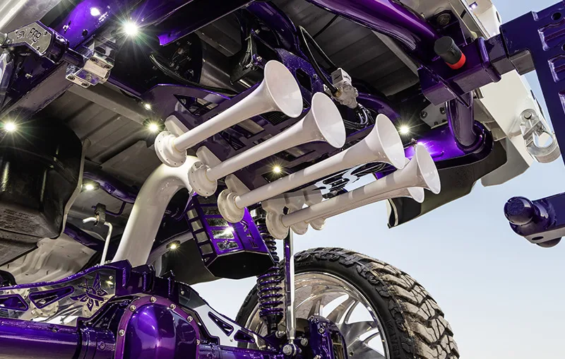 White train horns mounted under lifted truck with purple suspension