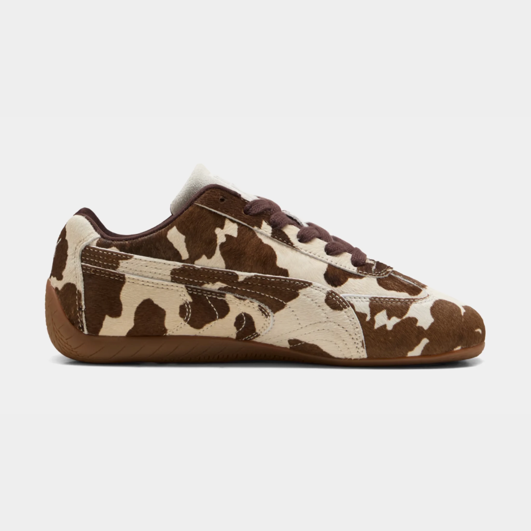 Brown and white cow-print sneakers on a neutral background.