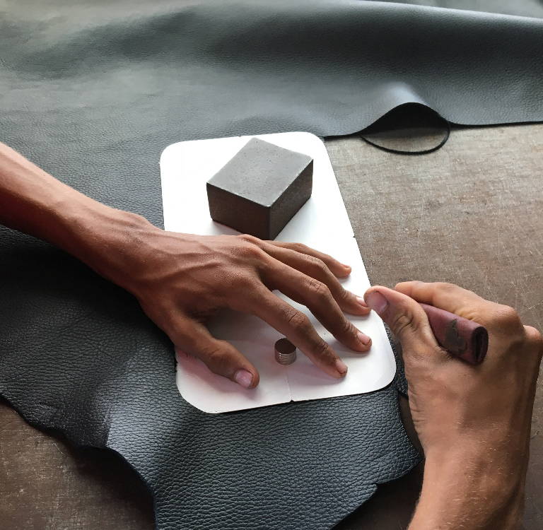 Two hands of a Brave Soles artisan preparing to craft leather shoes and sandals from upcycled leather.