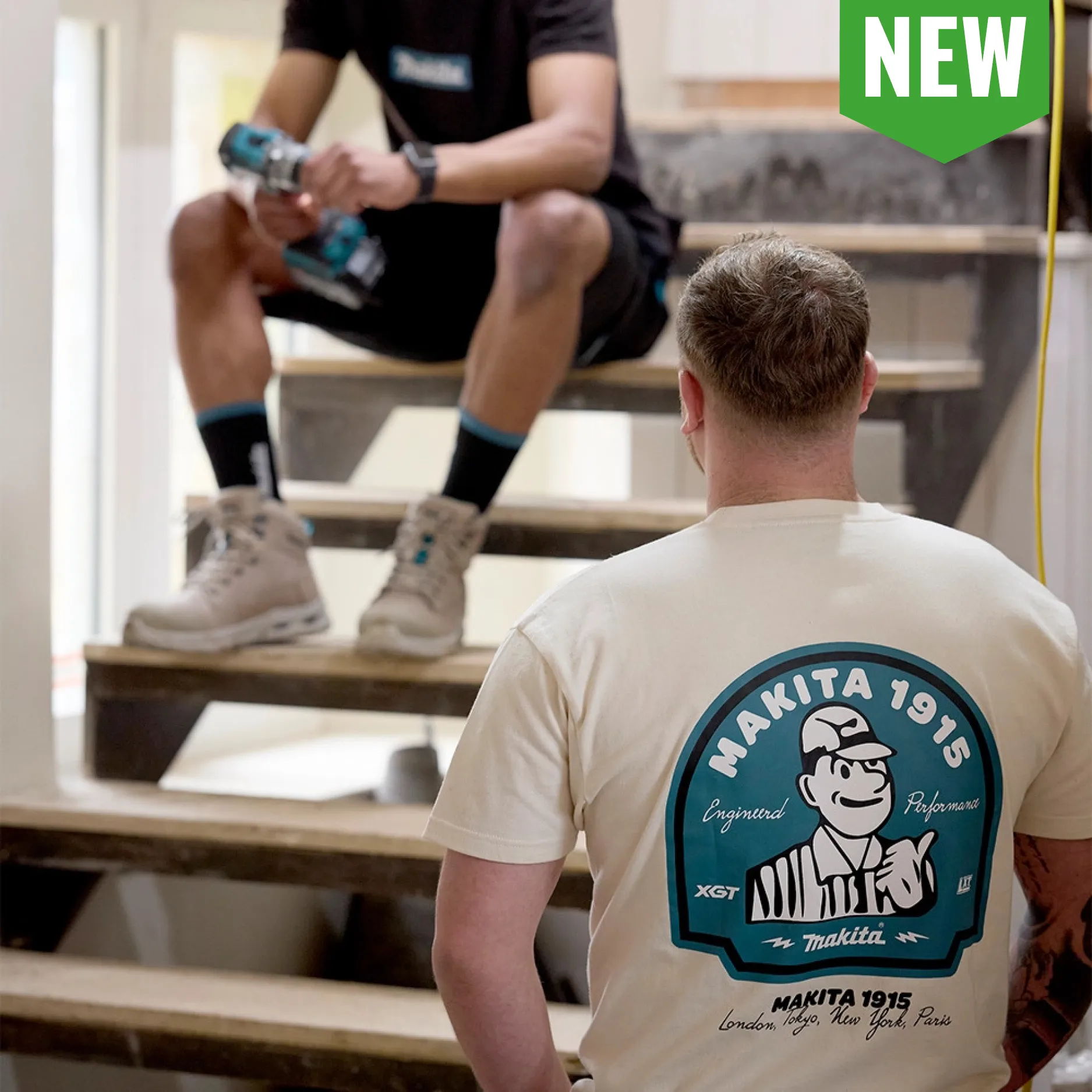 Two men on stairs; one wearing a Makita t-shirt, another holding a drink.