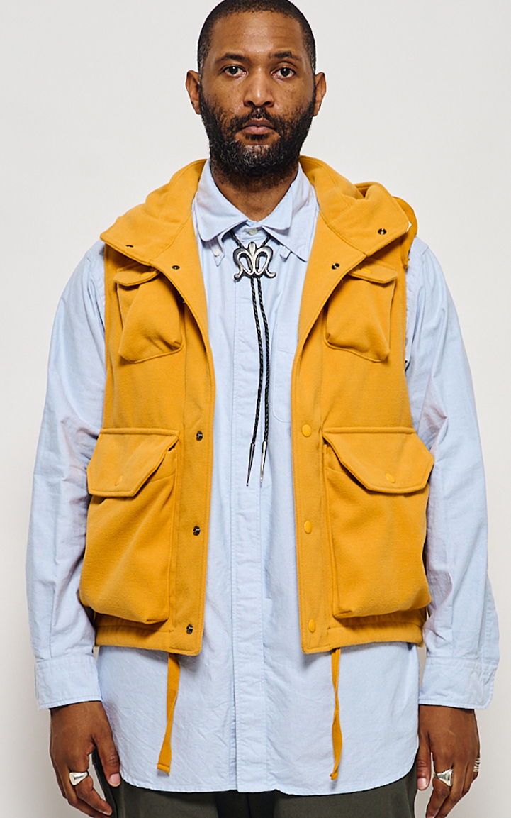 Man wearing a yellow vest over a light blue shirt.