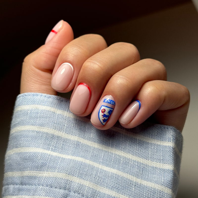 A hand with manicured nails featuring colorful designs and a striped shirt.