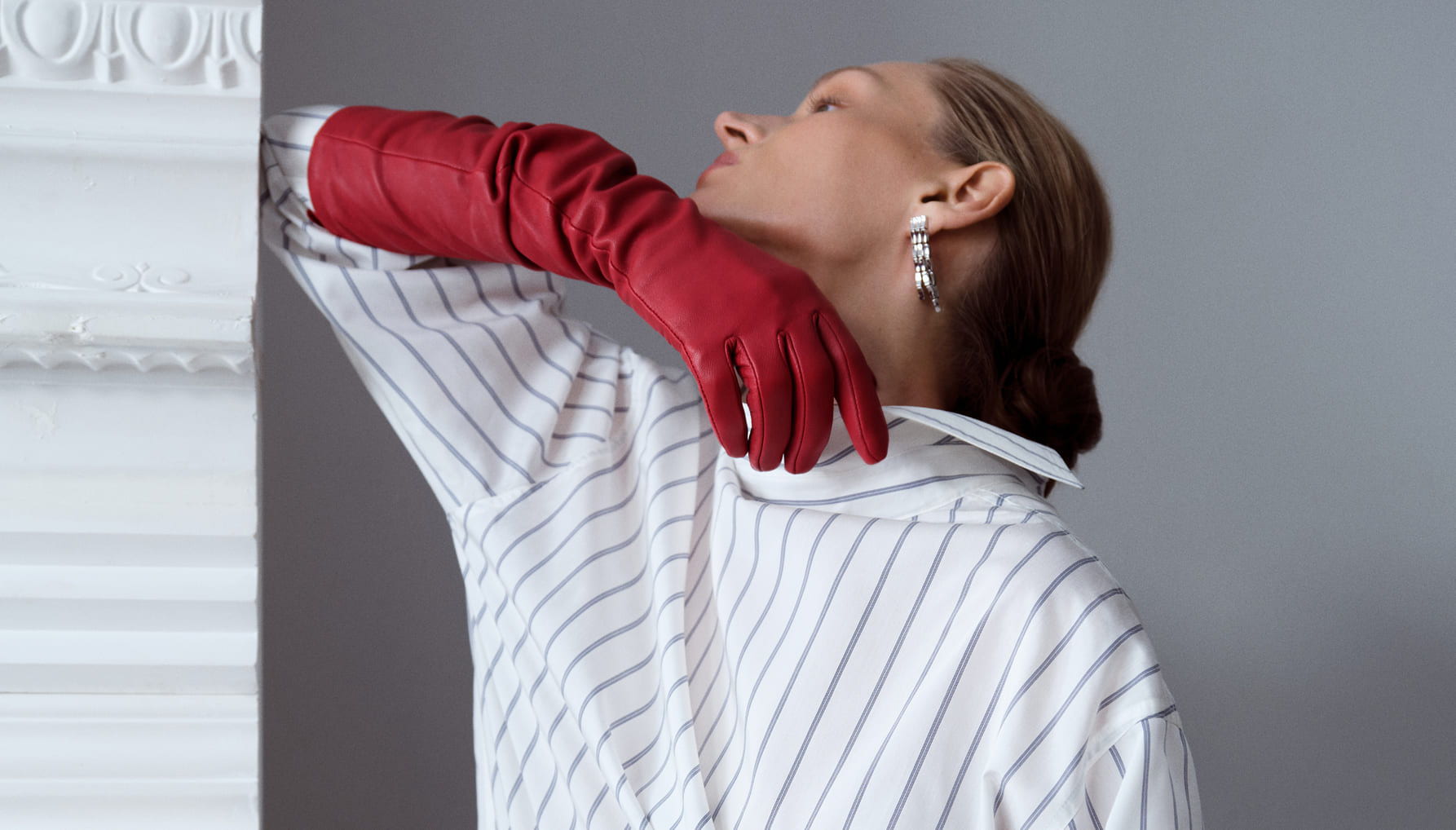 Model in red gloves poses elegantly with striped shirt.