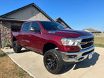 Front three-quarter view of lifted maroon Ram 1500 with chrome grille and off-road wheels