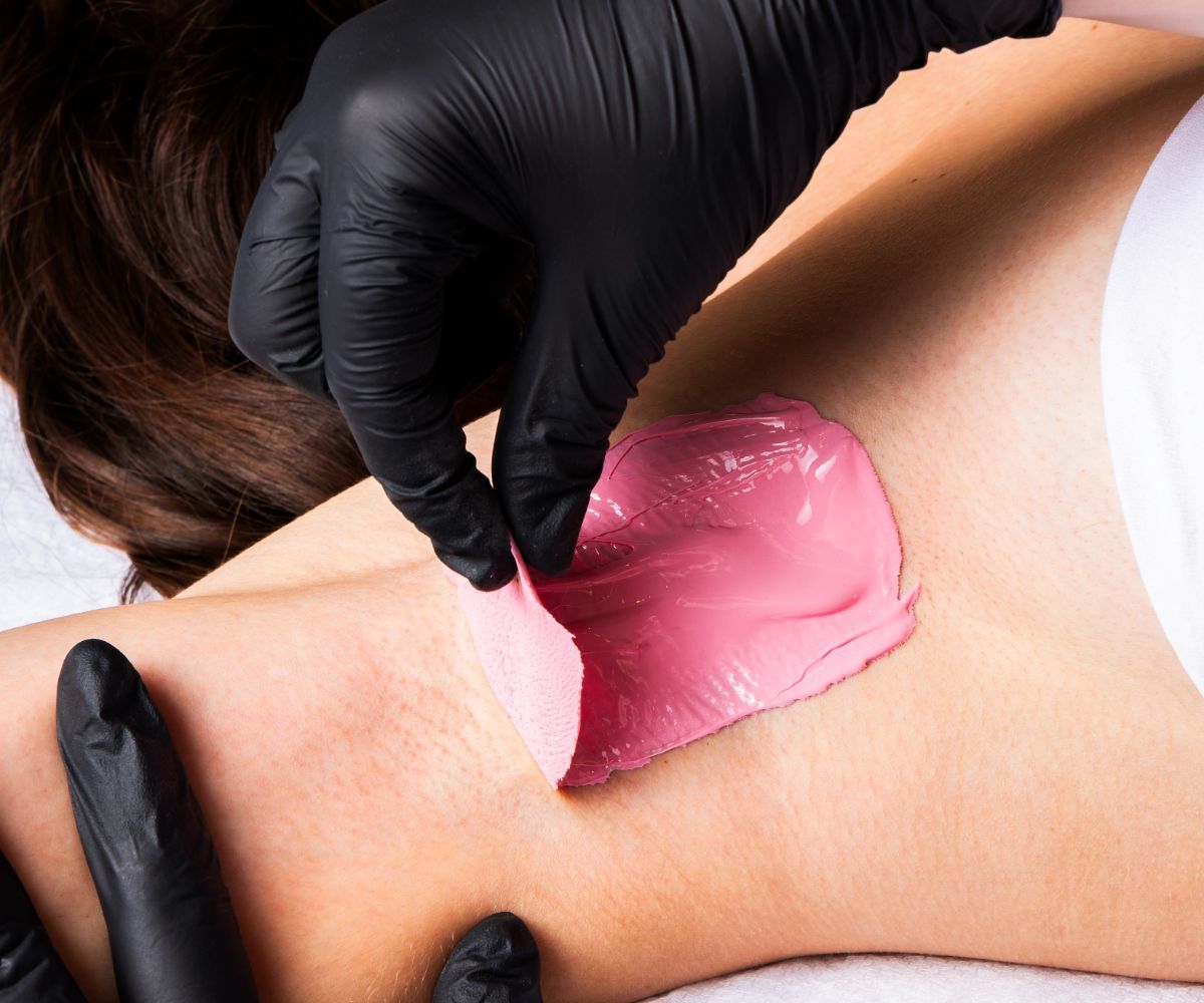 Person receiving a waxing treatment on their under arm with pink hot wax.