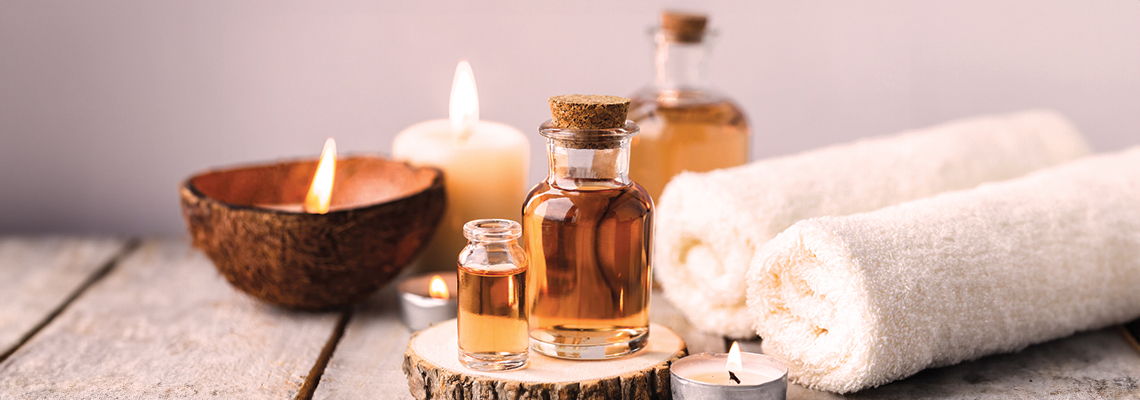 Spa essentials including oils, towels, and a candle on a wooden surface.