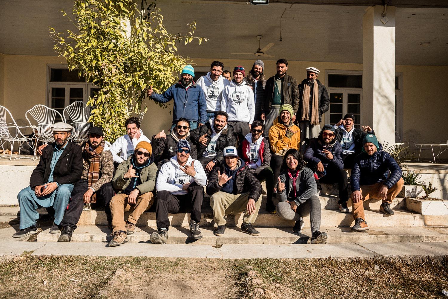 Group photo of individuals seated and standing outside a building.