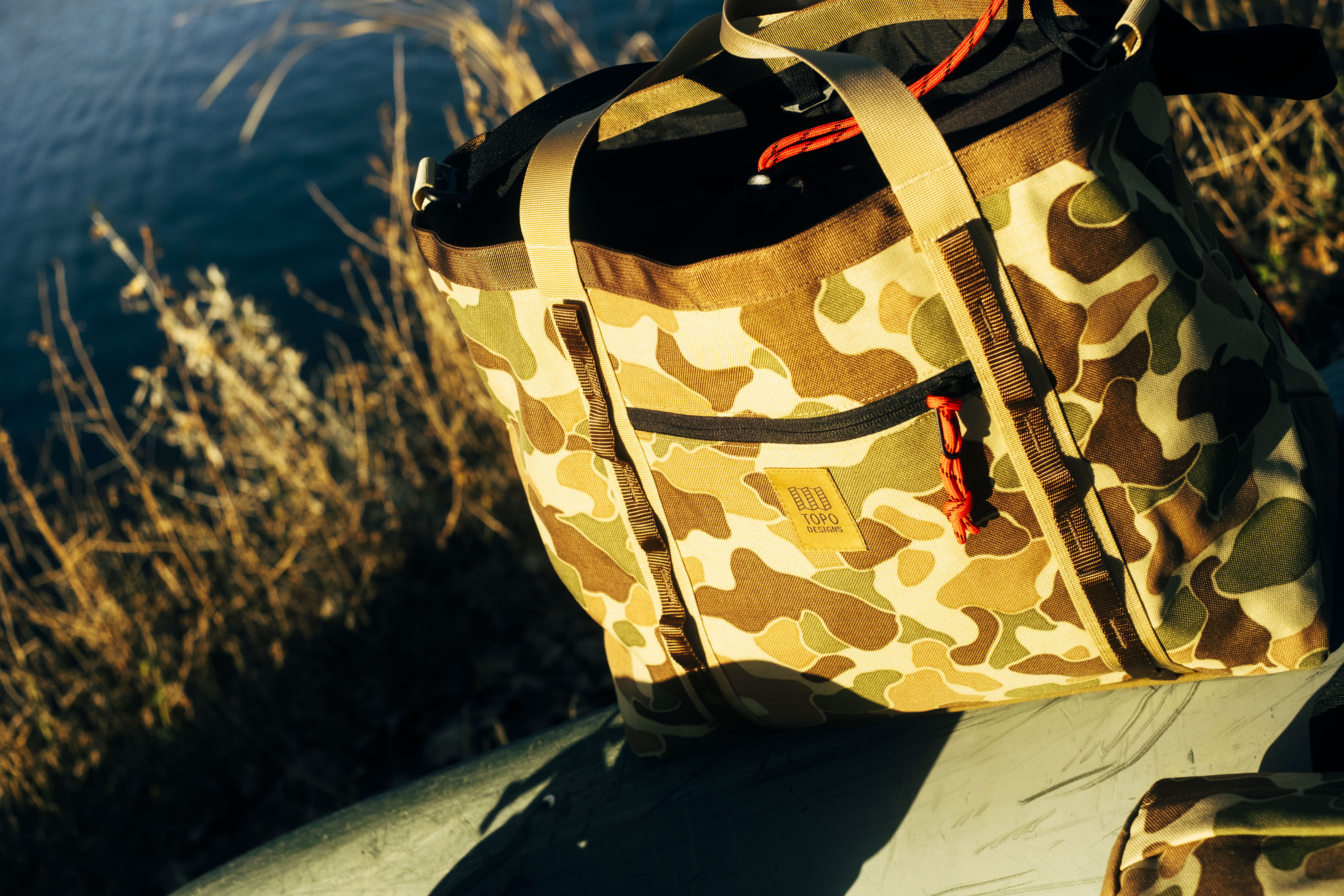 Camouflage bag resting on a surface near water.