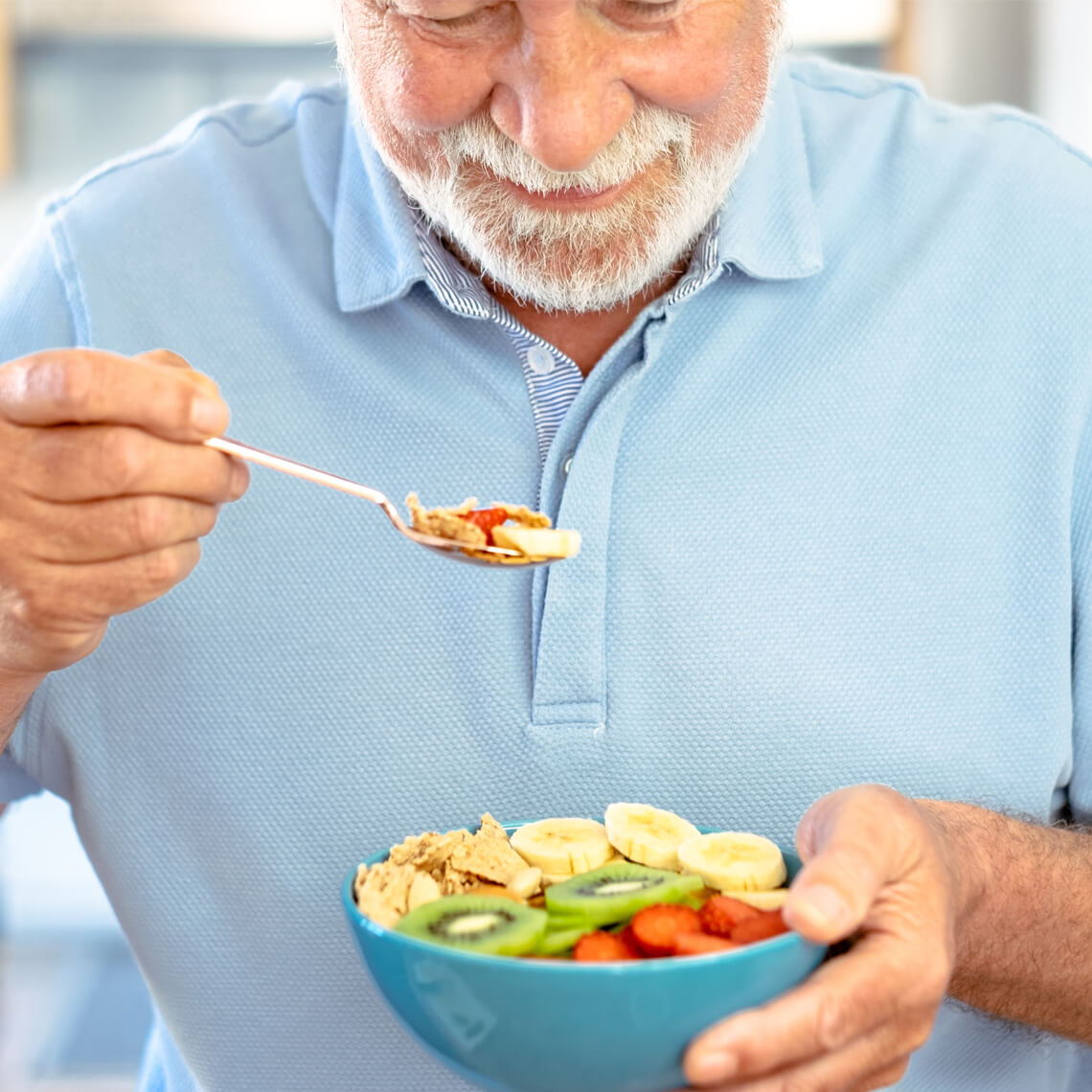 Smiling older man enjoying a colorful bowl of healthy food.