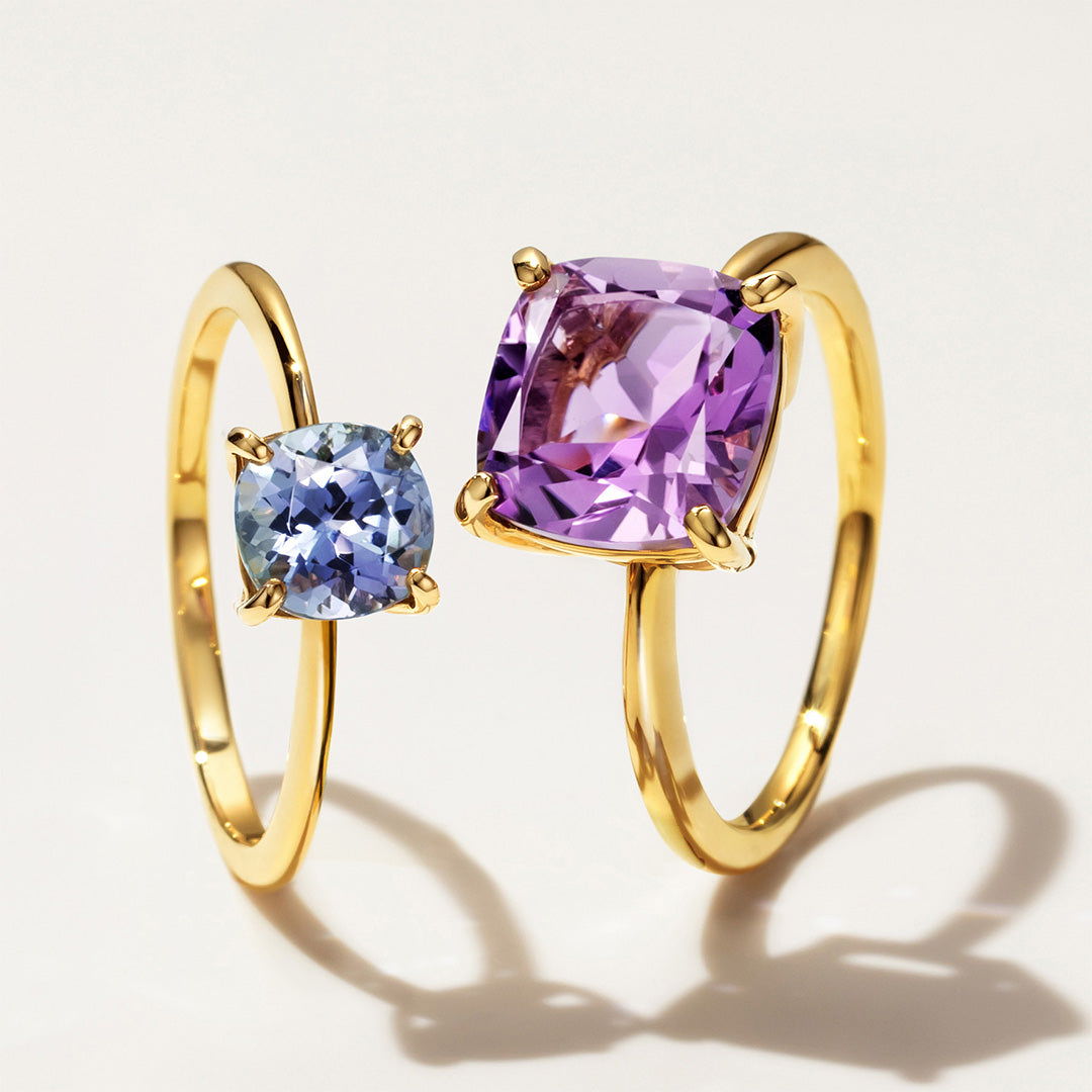 Two gold rings featuring blue and purple gemstones.