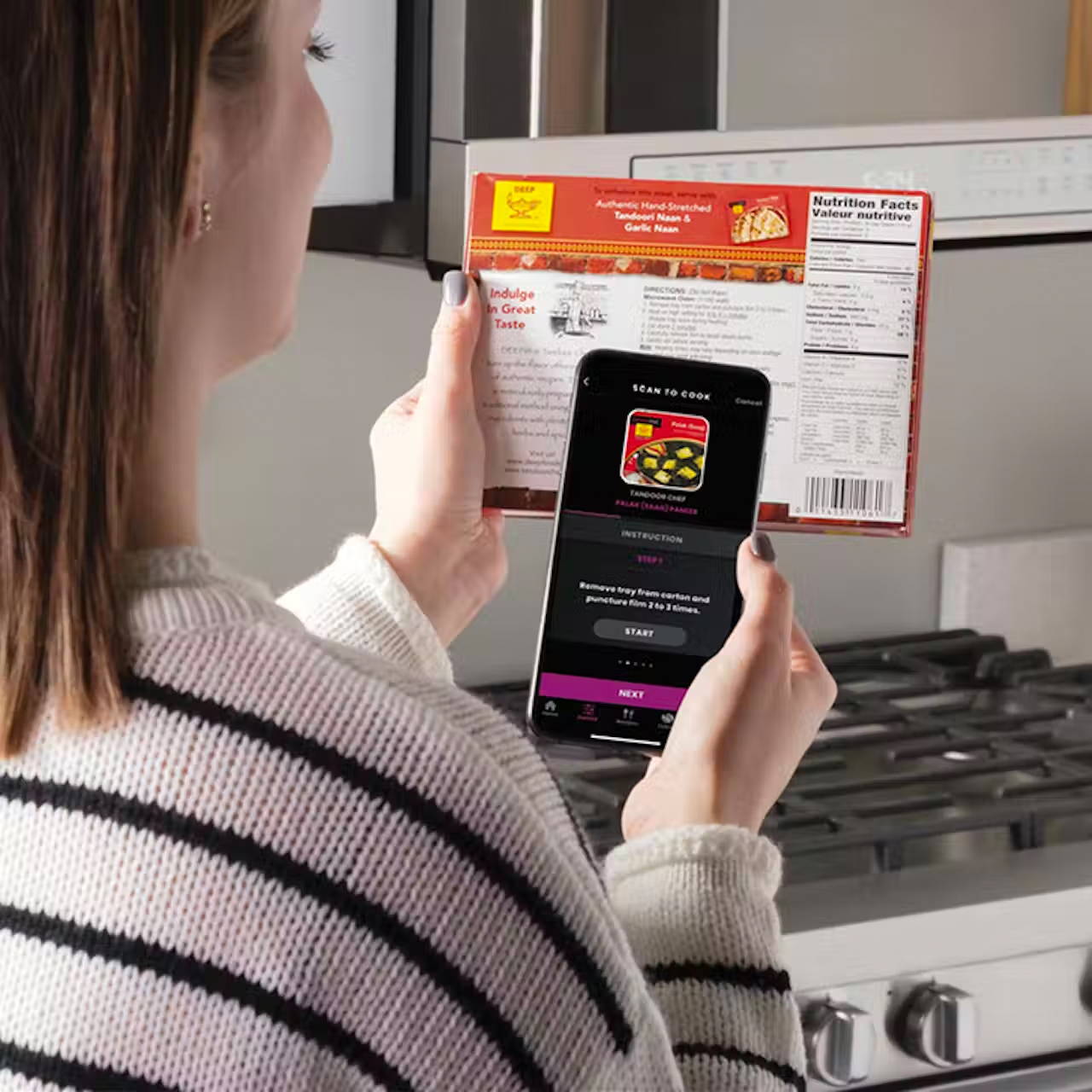 A woman holding her smart phone up using the scan -to-cook feature on the SmartHQ app.