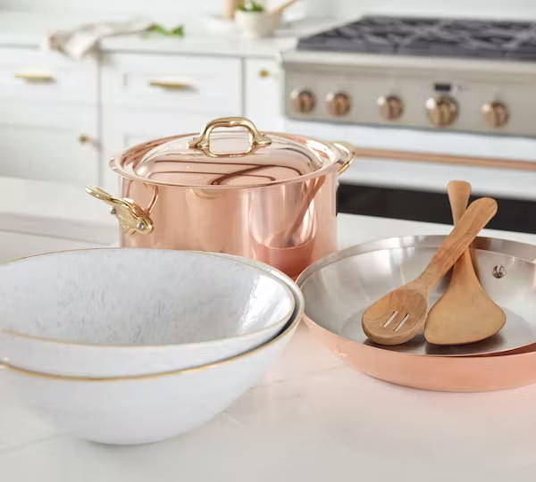 Copper pots and gold-rimmed bowls in white kitchen