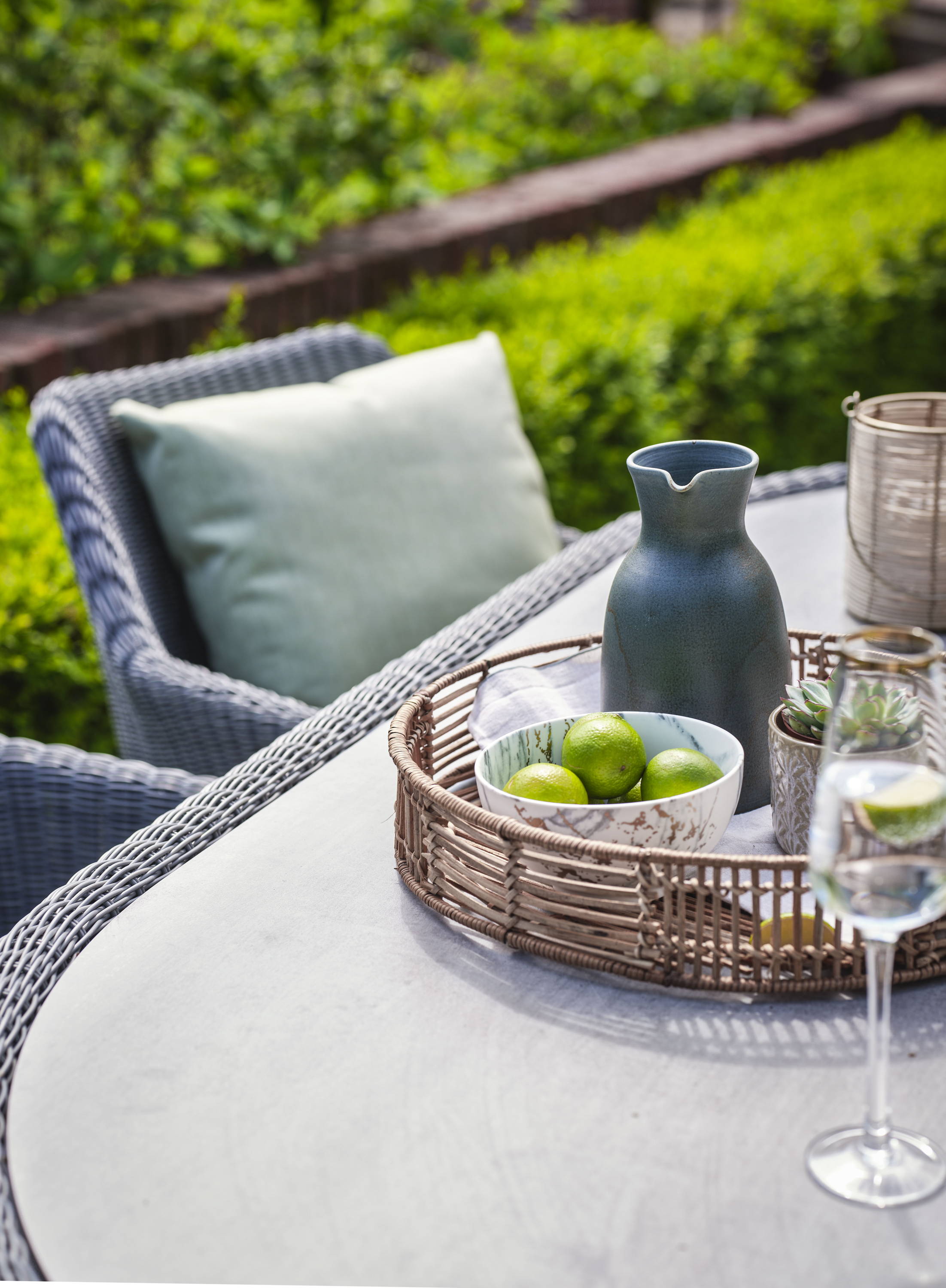Rattan and HPL garden furniture dining table with tray of food and champagne glass.