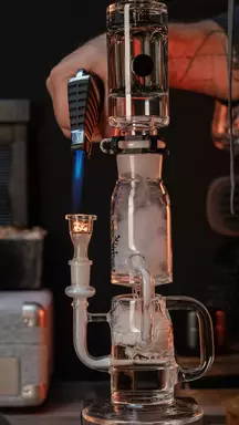 A person using a torch on their recycler glass dab rig