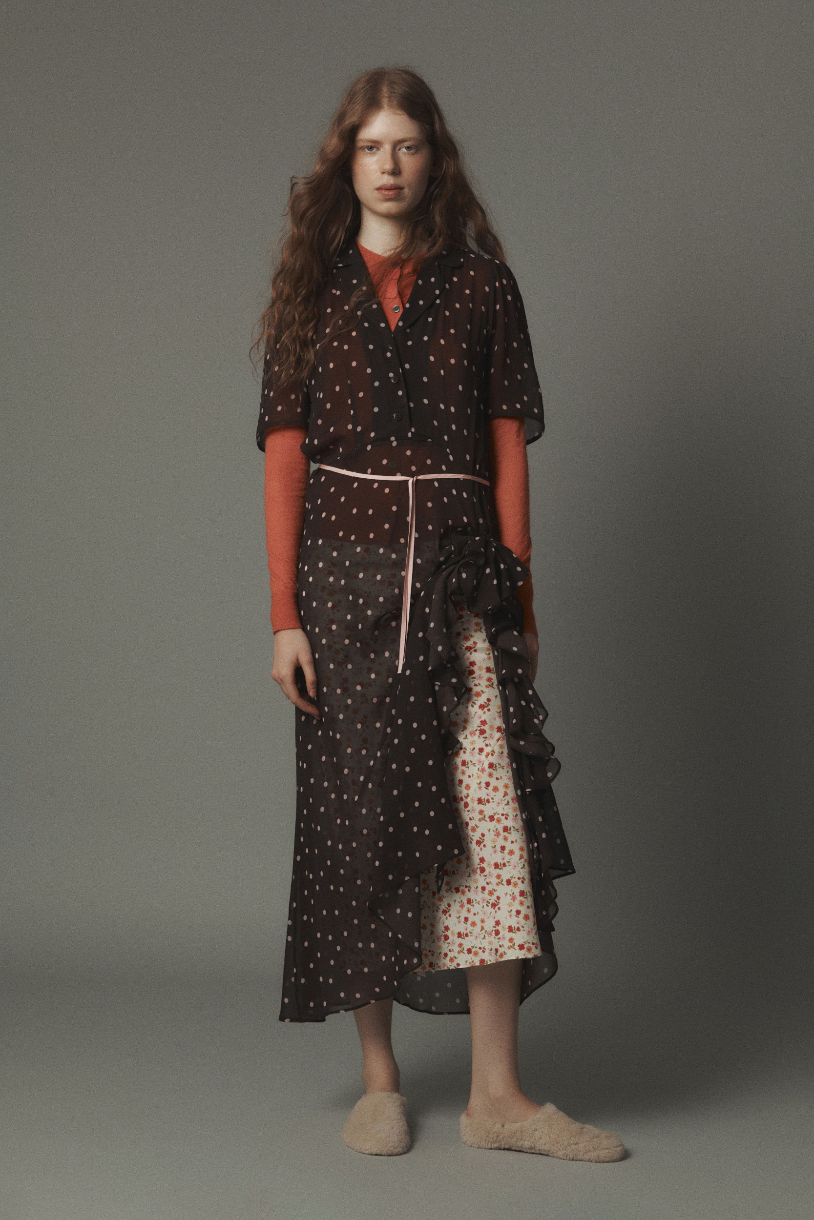 Model wearing a patterned dress with a belt, standing against a neutral background.