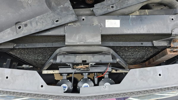 Close-up underside view of Flatlaw 127H train horn bells mounted behind front bumper on Joshua's 2005 Silverado 1500, install photo 3