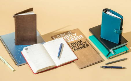 A Blue Sky planner surrounded by other bookbound planners and notebooks.