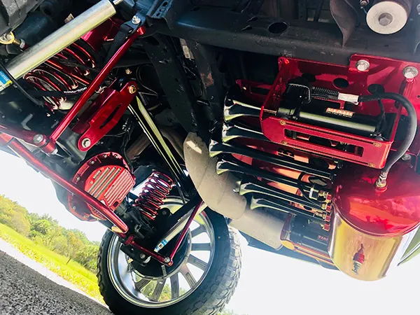 Underbody view showing black train horn bells, red mounting hardware, and polished air tank on Corey's 2018 Chevy Suburban, install photo 2
