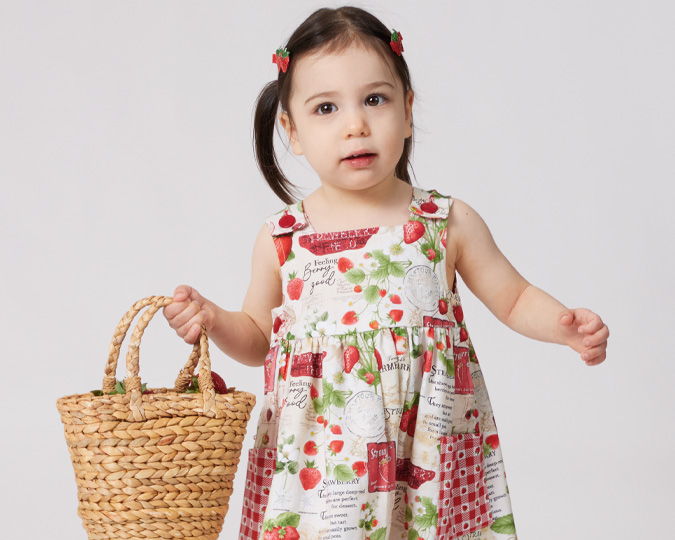 A young girl in a floral dress holding a woven basket.