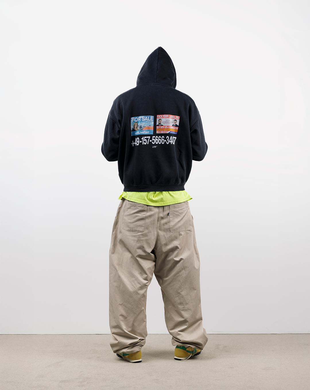 Person wearing a black hoodie and beige pants, viewed from behind.