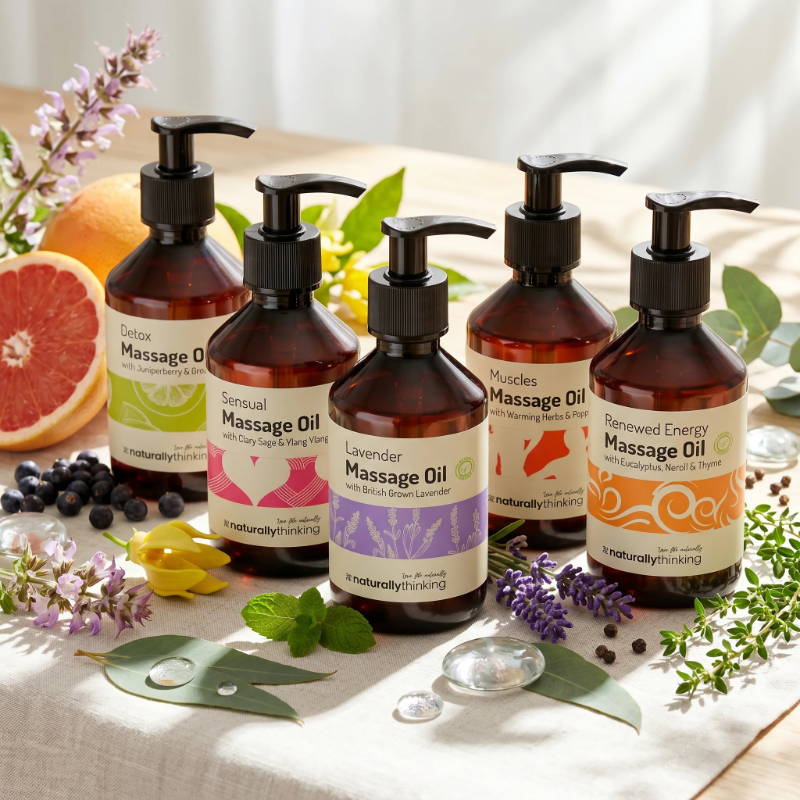 Bottles of massage oil surrounded by herbs and fruits on a table.