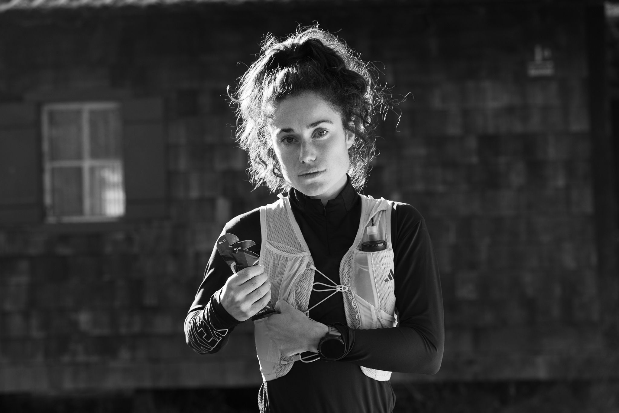 Trail-Läuferin Kimi Schreiber trägt eine Laufweste und hält zwei Energy Gels in der rechten Hand