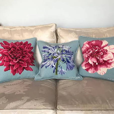 Finished Dahlia, Agapanthus, and Camellia needlepoint pillows on couch